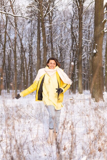 Schöne junge fröhliche Frau in einem verschneiten Landschaftswinterwald, der Spaß hat, freut sich im Winter und Schnee in der warmen Kleidung