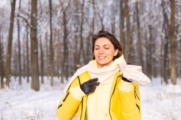 Schöne junge fröhliche Frau in einem verschneiten Landschaftswinterwald, der Spaß hat, freut sich im Winter und Schnee in der warmen Kleidung