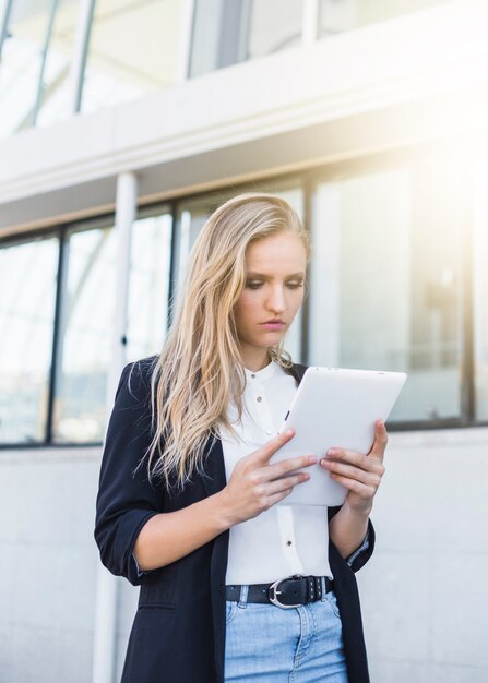 Schöne junge Geschäftsfrau, die digitale Tablette verwendet