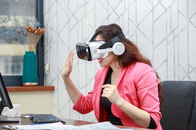 Schöne junge Geschäftsfrau, die eine VR-Brille trägt und ihre Hand schüttelt Foto in hoher Qualität