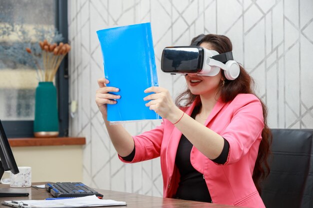 Schöne junge Geschäftsfrau, die eine VR-Brille trägt und versucht, ihre Notiz zu sehen Hochwertiges Foto
