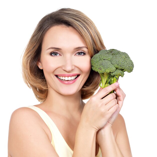 Schöne junge gesunde Frau hält Brokkoli lokalisiert auf Weiß.