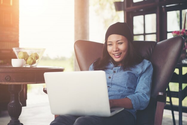 Schöne junge Hipster Frau mit ihrem Laptop und Kaffee sitzen