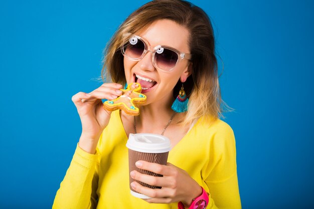 Schöne junge Hipsterfrau, die Kekse isst, Kaffee trinkend