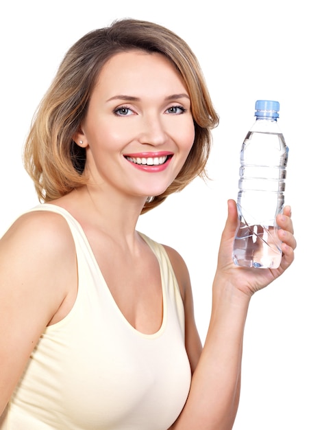 Schöne junge lächelnde Frau mit einer Flasche Wasser auf Weiß.