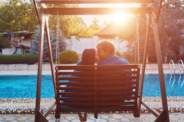 Kostenloses Foto schöne junge paare, die an der bank durch das pool sitzen