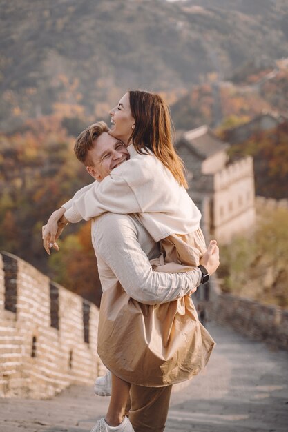 Schöne junge Paare, die an der Chinesischen Mauer umarmen