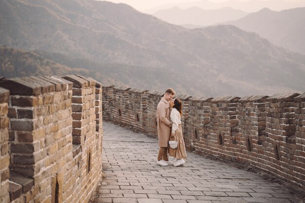 Schöne junge Paare, die Neigung auf der Chinesischen Mauer zeigen