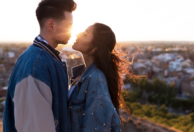 Schöne junge Paare in der Liebe, die an einer Gebäudedachspitze bei dem Sonnenuntergang steht.