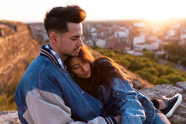 Schöne junge Paare in der Liebe, die an einer Gebäudedachspitze bei dem Sonnenuntergang steht.