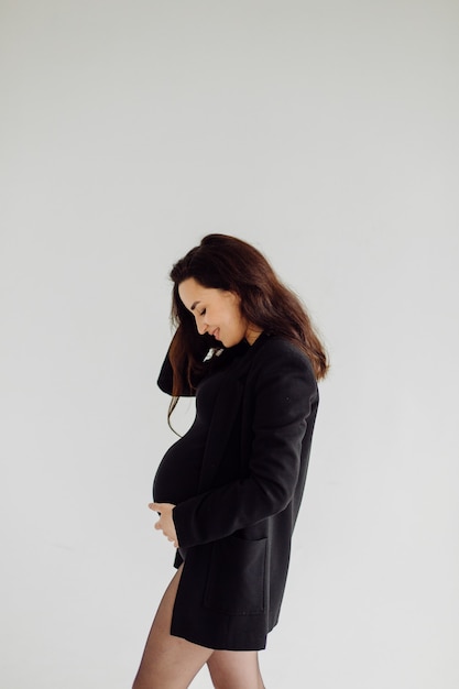 Schöne junge schwangere Frau, die im Studio im Kleid aufwirft