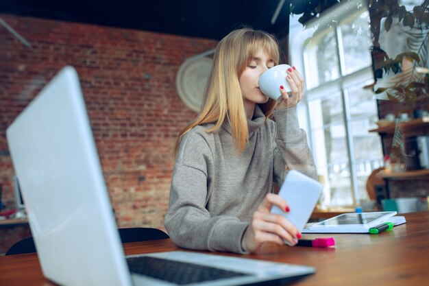 Schöne kaukasische Geschäftsdame, die im Büro mit Laptop arbeitet