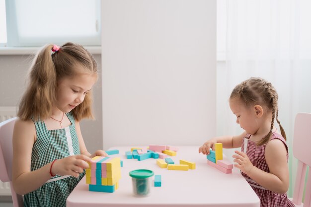 Schöne kaukasische Mädchen, die mit mehrfarbigen Holzblöcken spielen