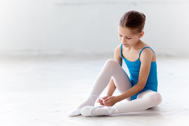 Schöne kleine Ballerina im blauen Kleid zum Tanzen, die auf Fußspitzenschuhen setzt