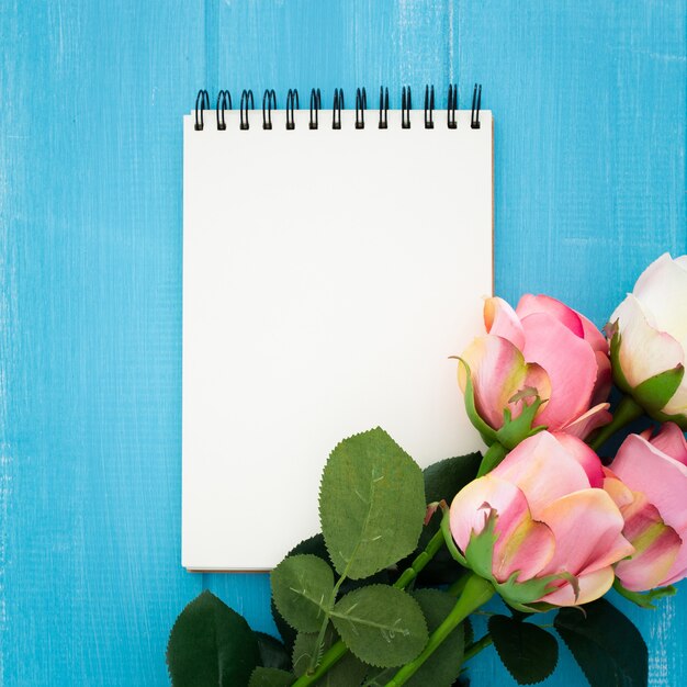 schöne Komposition mit Notebook und Rosen auf blauem Holz