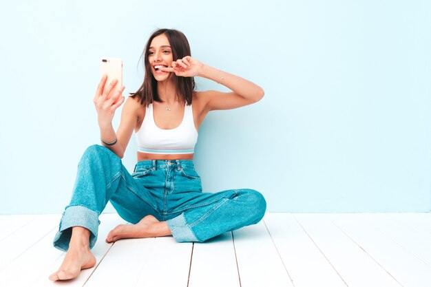 Schöne lächelnde Frau in weißem Jersey-Top-Shirt und Jeans gekleidet. sorglos fröhliches Model genießt ihren Morgen