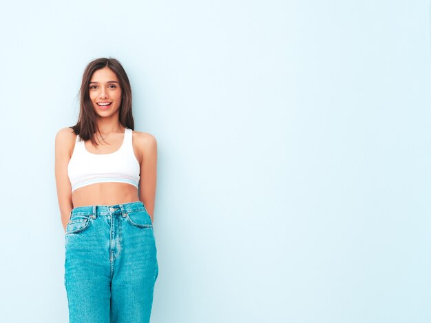 Schöne lächelnde Frau in weißem Jersey-Top-Shirt und Jeans gekleidet