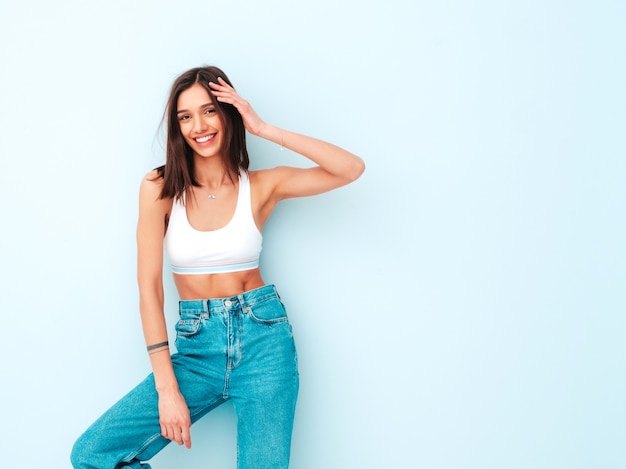 Schöne lächelnde Frau in weißem Jersey-Top-Shirt und Jeans gekleidet