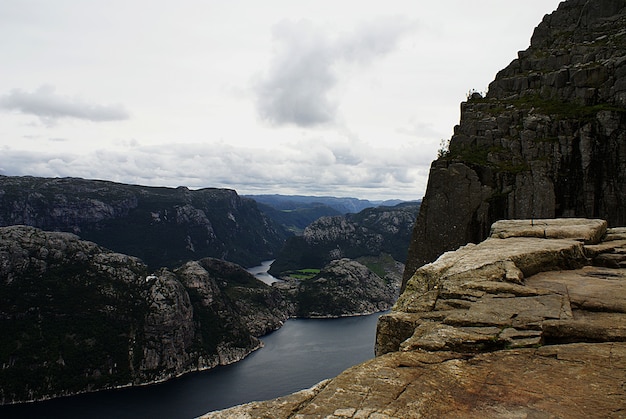 Schöne Landschaft der berühmten Preikestolen Klippen nahe einem See unter einem bewölkten Himmel in Stavanger, Norwegen