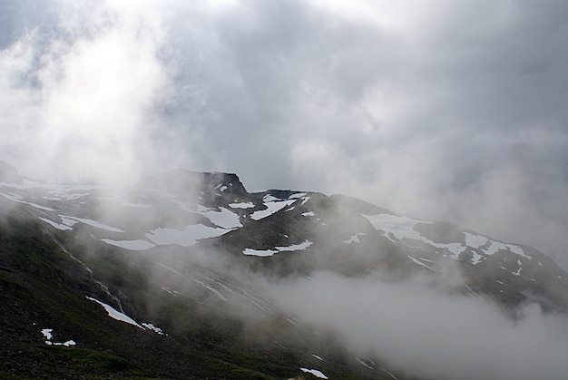 Schöne Landschaft der hohen felsigen Berge bedeckt mit Schnee, der im Nebel in Norwegen umhüllt wird