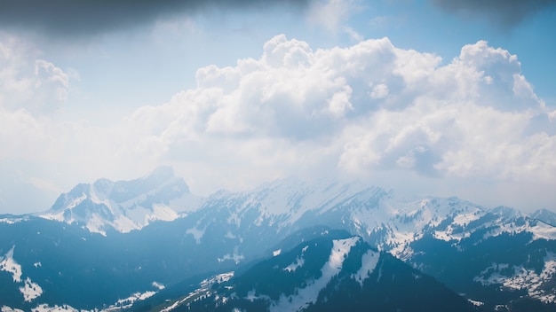 Schöne Landschaft der weißen flauschigen Wolken, die hohe Berge während des Tages bedecken