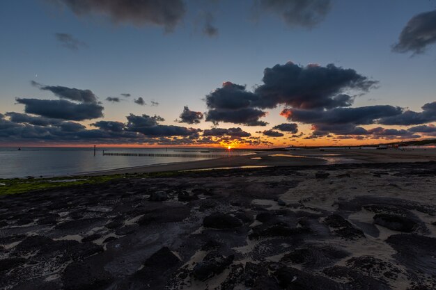 Schöne Landschaft eines atemberaubenden Sonnenuntergangs über dem ruhigen Ozean in Westkapelle, Zeeland