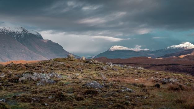 Schöne Landschaft eines Feldes, umgeben von Hügeln unter dem düsteren Himmel