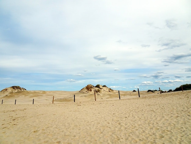 Schöne Landschaft eines Sandstrandes unter einem bewölkten Himmel in Leba, Polen