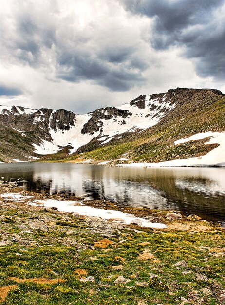 Schöne Landschaft eines Sees, umgeben von hohen felsigen schneebedeckten Bergen unter einem bewölkten Himmel