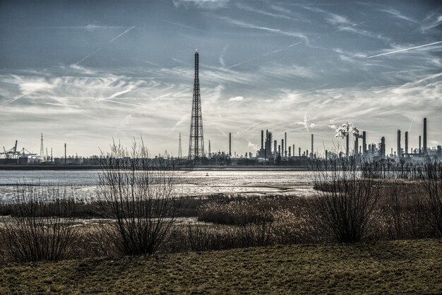 Schöne Landschaft von Industriegebäuden am Ufer, umgeben von Gras unter atemberaubendem Himmel