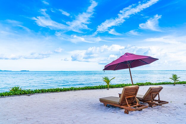 Schöne Landschaft von Strandseeozean mit leerer Stuhlplattform und fast Kokosnusspalme des Regenschirmes mit weißer Wolke und blauem Himmel