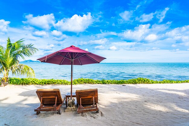 Schöne Landschaft von Strandseeozean mit leerer Stuhlplattform und fast Kokosnusspalme des Regenschirmes mit weißer Wolke und blauem Himmel