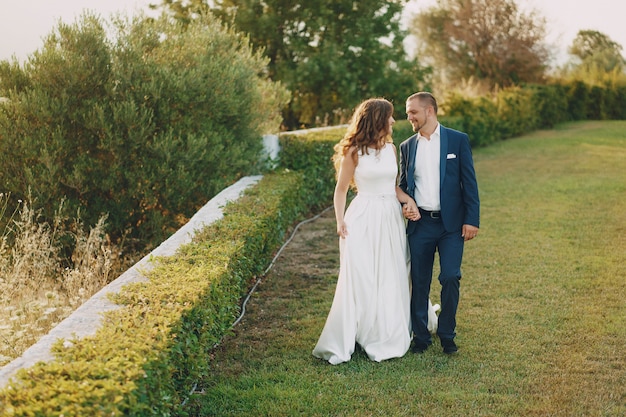 Schöne langhaarige Braut im weißen Kleid mit ihrem jungen Mann, der in die Natur geht