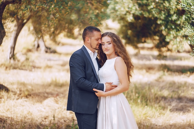 Schöne langhaarige Braut im weißen Kleid mit ihrem jungen Mann, der in die Natur geht