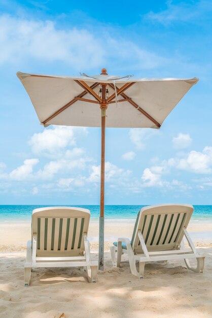 Schöne Liegestühle mit Sonnenschirm am tropischen weißen Sand beac