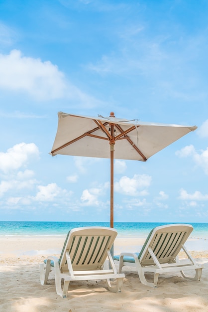 Schöne Liegestühle mit Sonnenschirm am tropischen weißen Sand beac