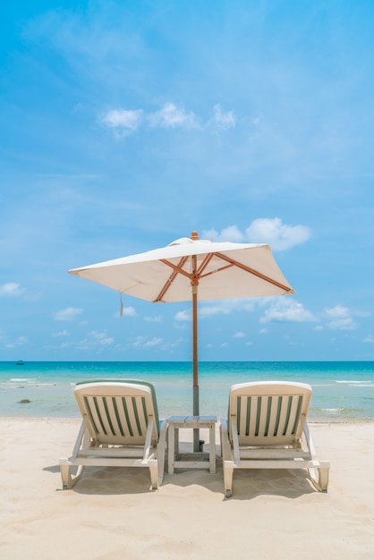 Schöne Liegestühle mit Sonnenschirm am tropischen weißen Sand beac