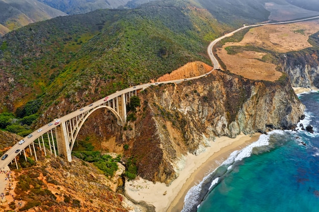 Kostenloses Foto schöne luftaufnahme von grünen hügeln und einer kurvigen schmalen brücke entlang der klippen