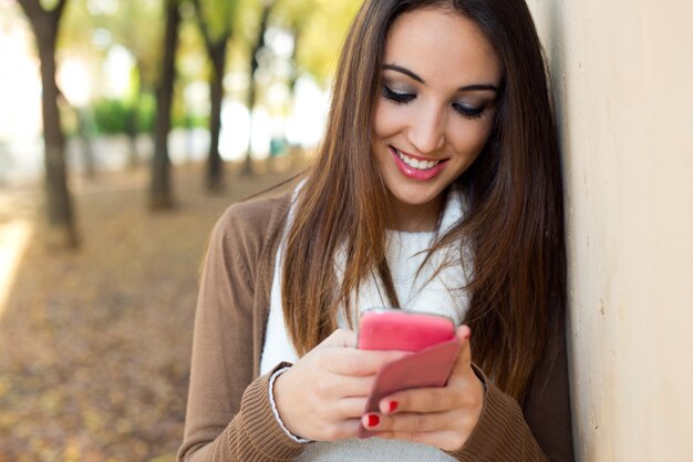 Schöne Mädchen chatten mit Handy im Herbst.