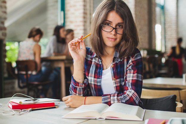 Schöne Mädchen posiert mit Buch am Tisch