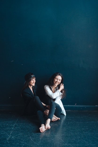 Schöne Mädchen sitzen an der Wand und posieren