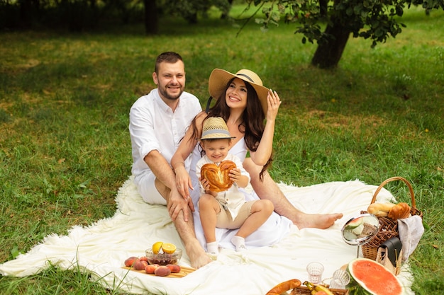 Schöne Mama, Papa und ihr süßes kleines Kind haben Spaß zusammen und lächeln draußen