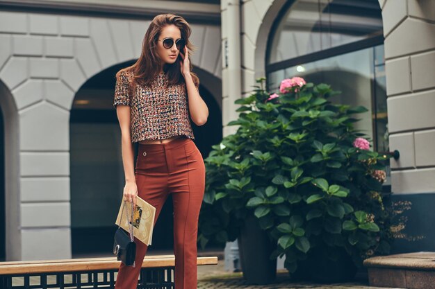 Schöne modische Brünette mit trendiger Kleidung und Sonnenbrille.