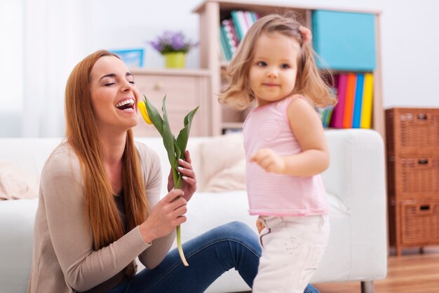 Schöne Mutter, die die Blume genießt, die sie von der Tochter erhielt