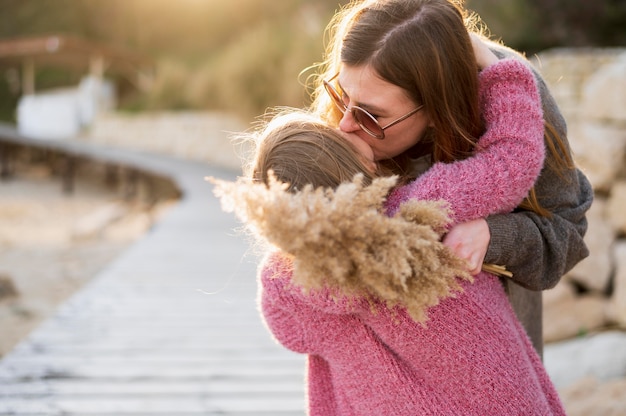 Schöne Mutter, die Kind draußen küsst