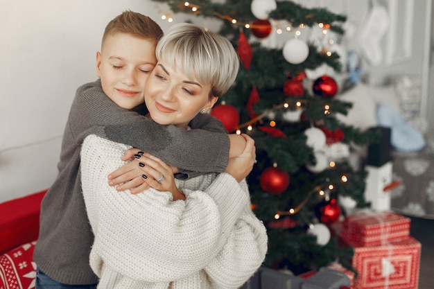 Schöne Mutter in einem weißen Pullover. Familie in einer Weihnachtsdekoration. Kleiner Junge in einem Raum