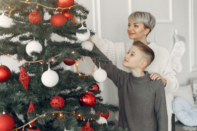 Schöne Mutter in einem weißen Pullover. Familie in einer Weihnachtsdekoration. Kleiner Junge in einem Raum