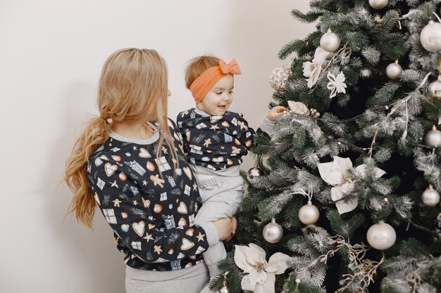 Schöne Mutter mit Kind. Familie in Weihnachtsatmosphäre. Leute, die Weihnachtsbaum tragen.