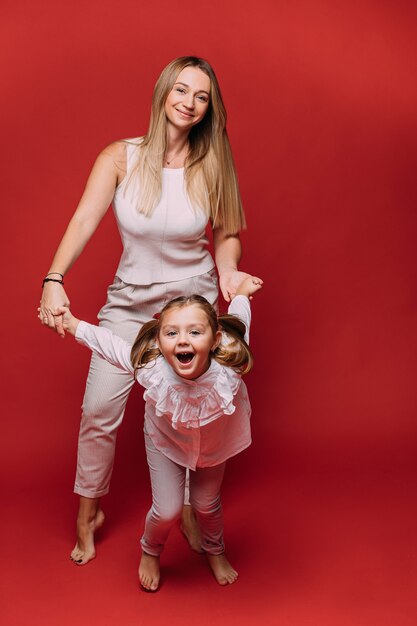 Schöne Mutter viel Spaß mit ihrer hübschen Tochter und Lächeln, Bild einzeln auf rotem Hintergrund