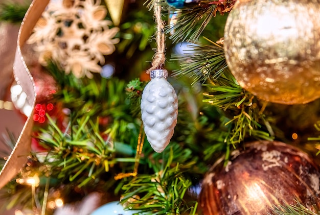 Schöne Nahaufnahme einer weißen Verzierung und anderer Dekorationen auf einem Weihnachtsbaum mit Lichtern